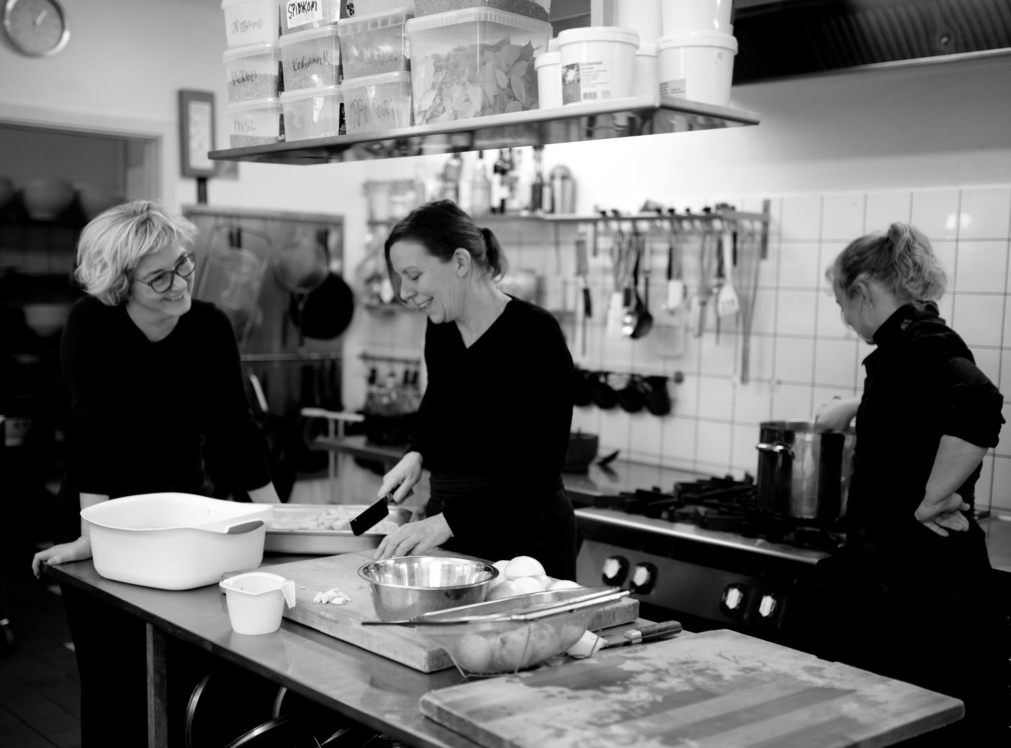 Black and white company of female cooks preparing food in kitchen of cafe while interacting and smiling