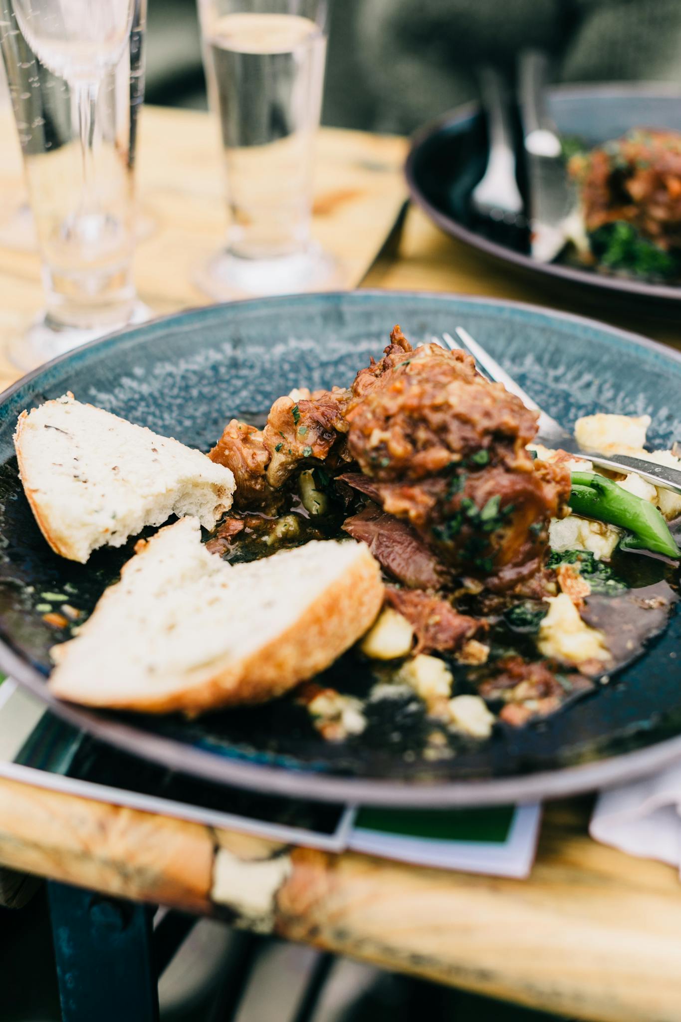 Delicious meat dish served with bread on plate with cutlery on table with glassware in modern cafe on blurred background