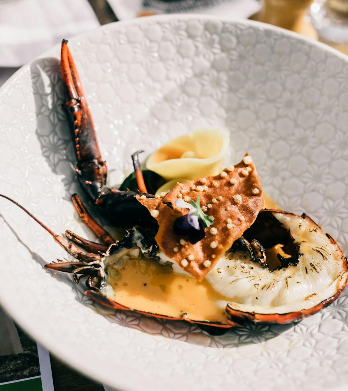 From above of appetizing fresh lobster served on white plate on table near seasoning n luxury restaurant with gourmet food